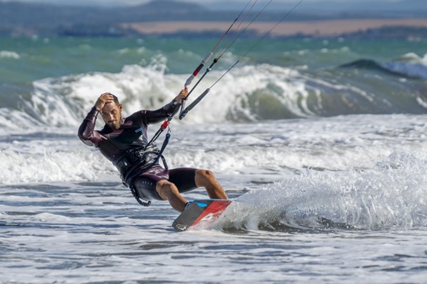 Mężczyzna uprawiający kiteboardingu na morzu.